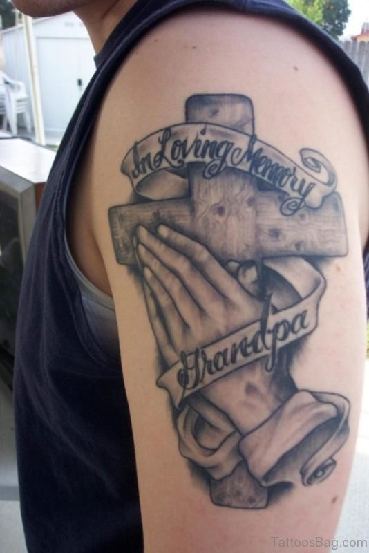 Grey Ink Cross In Praying Hands With Banner Tattoo Shoulder